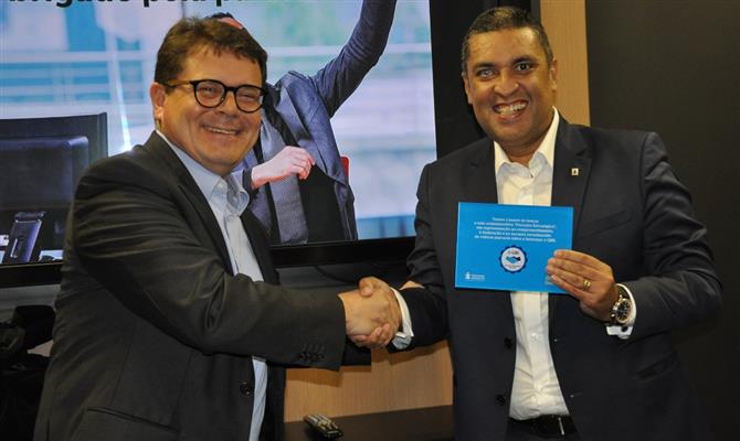 Peter Rebrin, CEO da QBE no Brasil, entrega o selo de excelência da empresa à Intermac, do CEO Eduardo Aoki