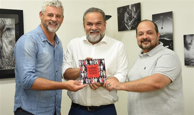 Ricardo Gomes e Marcelo Michieletto, da Câmara LGBT, em visita à PANROTAS, entregam azulejo pró-diversidade ao editor-chefe Artur Luiz Andrade