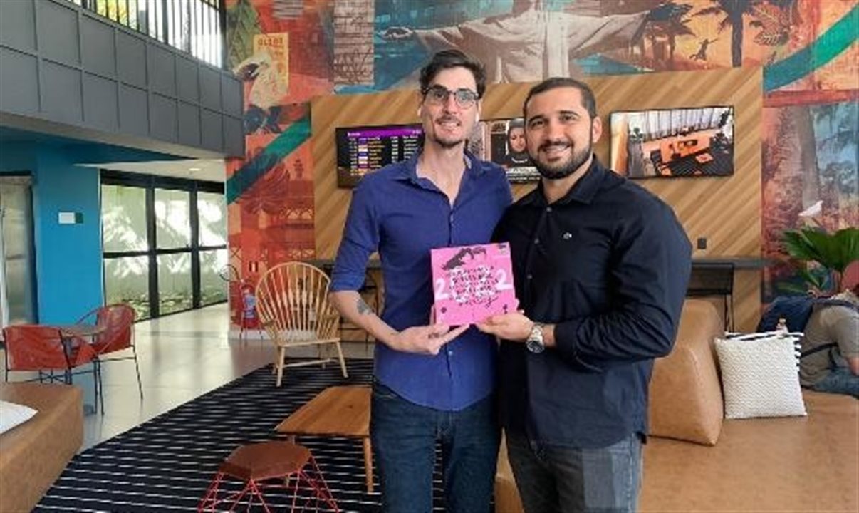 André Loyola, representante da Câmara LGBT no Rio, entrega o azulejo 2022 da entidade para Guilherme Martins, gerente geral do Linx Galeão