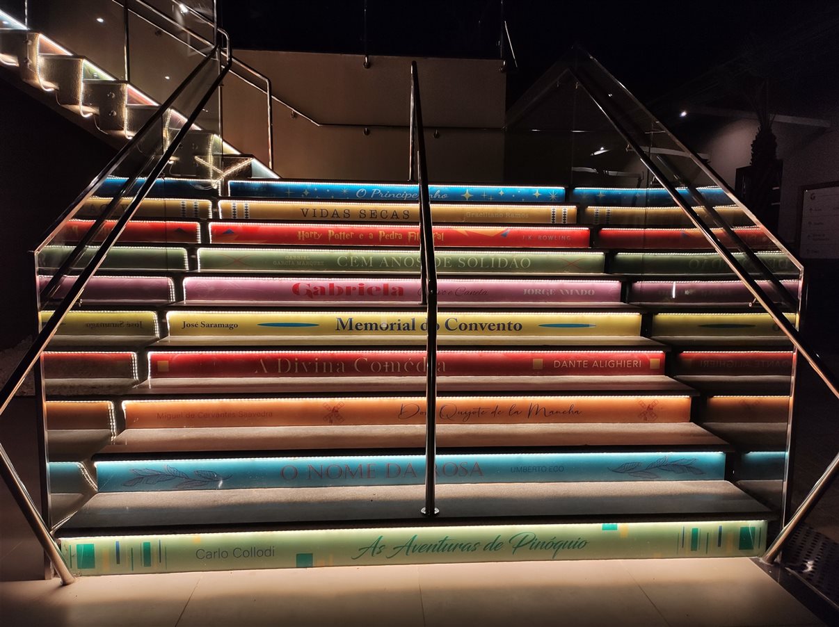 Escada com os nomes de grandes obras iluminada durante a noite