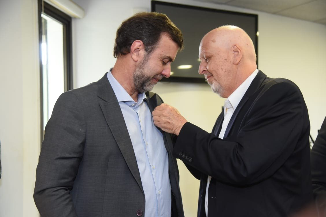 Marcelo Freixo recebeu, em 2023, das mãos do eterno Marcelo Sanovicz, o pin da marca Aquarela do Brasil