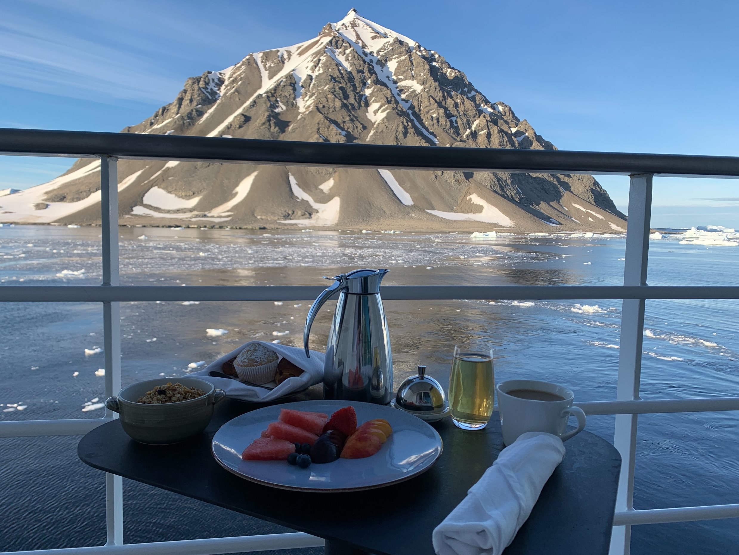 Café da manhã na cabine com vista para montanhas nevadas e icebergs