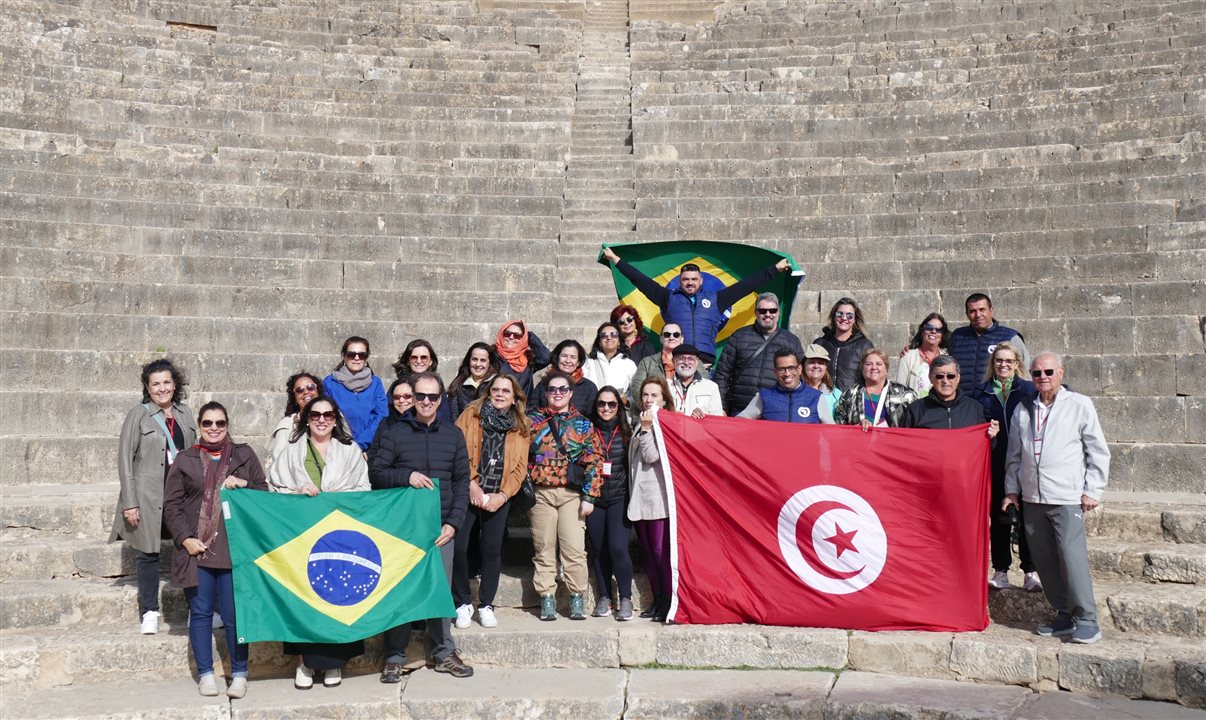 Agentes de viagens estendem bandeiras da Tunísia e do Brasil no anfiteatro romano do Sítio Arqueológico de Dougga