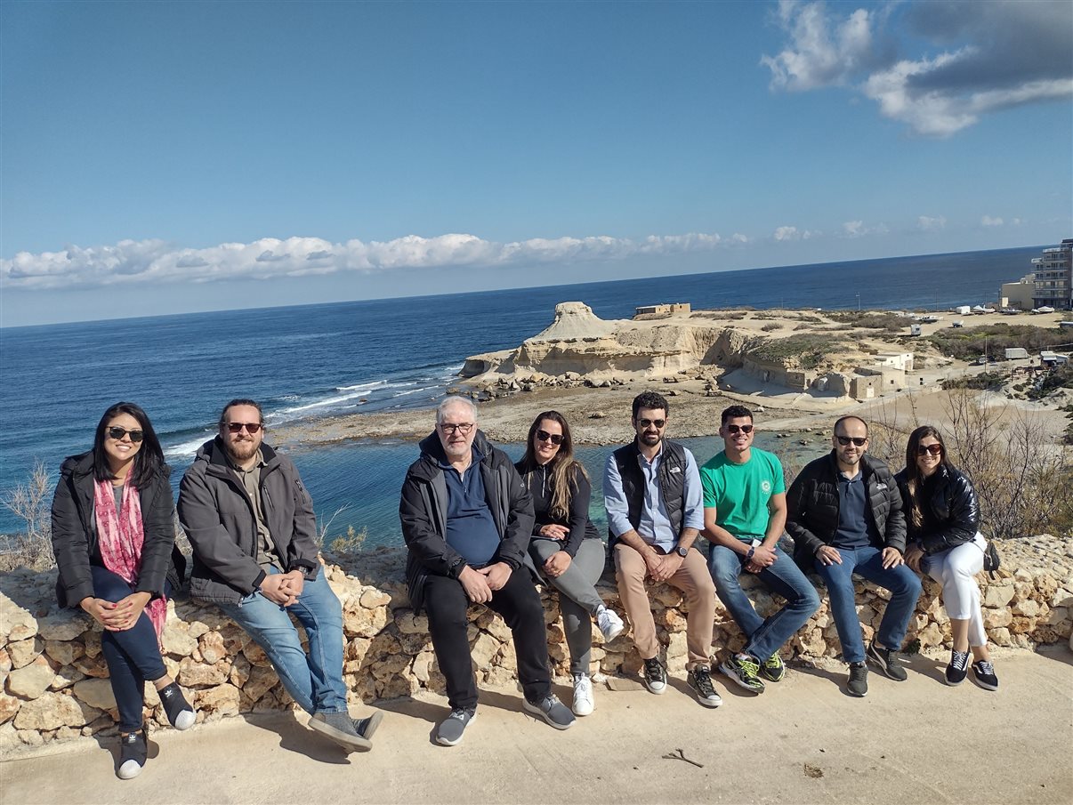 Profissionais do famtour em Malta posam com o litoral da ilha de Gozo