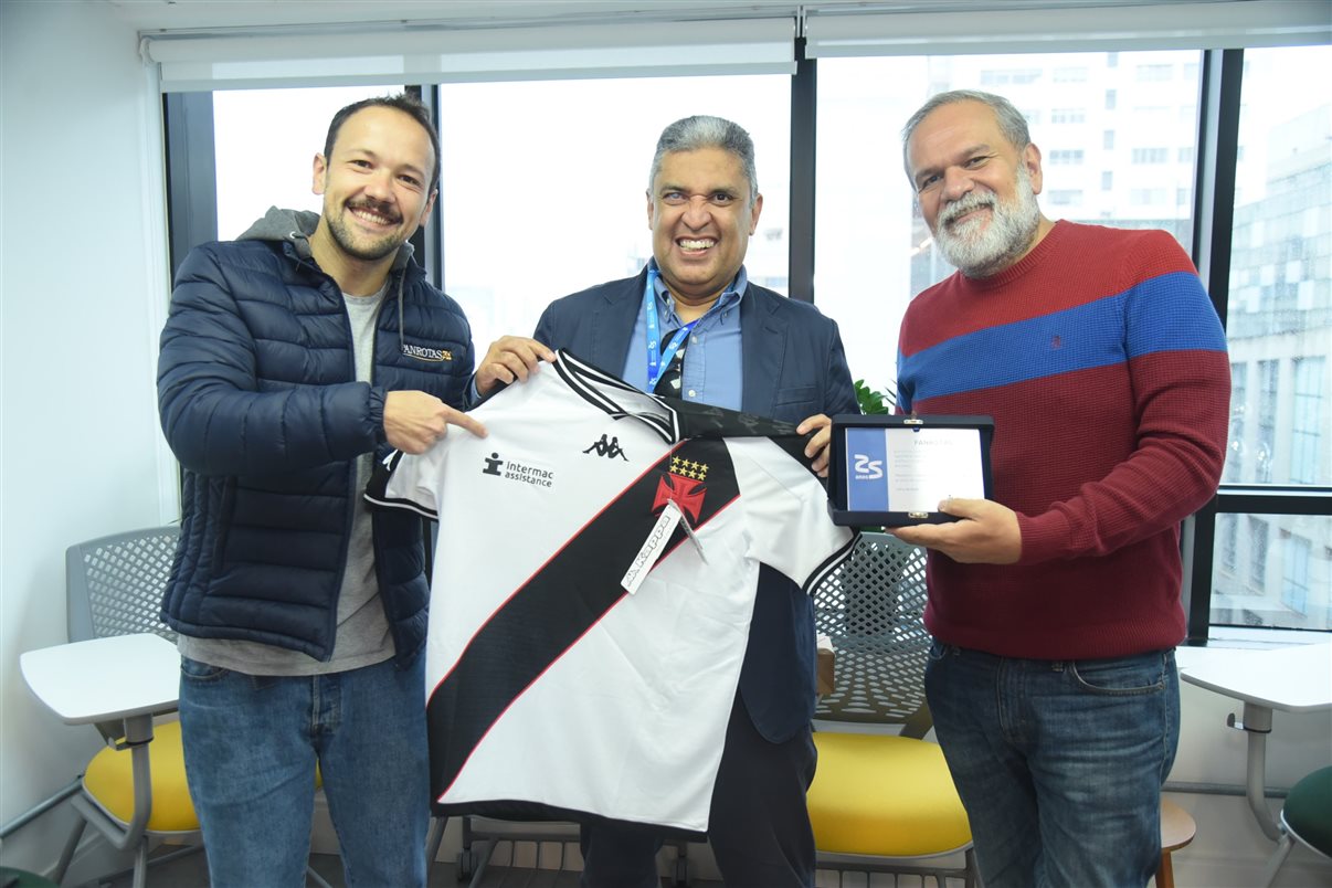 CEO da Intermac, Eduardo Aoki, ao centro, presenteia Rodrigo Vieira e Artur Luiz Andrade, da PANROTAS, com placa e camisa do Vasco da Gama. Empresa de seguro viagem patrocina o clube brasileiro, assim como grandes times de futebol sul-americanos