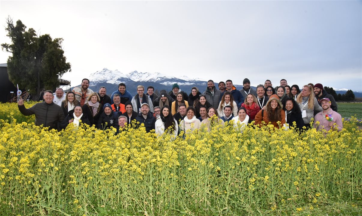 Grupo em meio as flores em Trevelin; ao fundo, uma montanha nevada