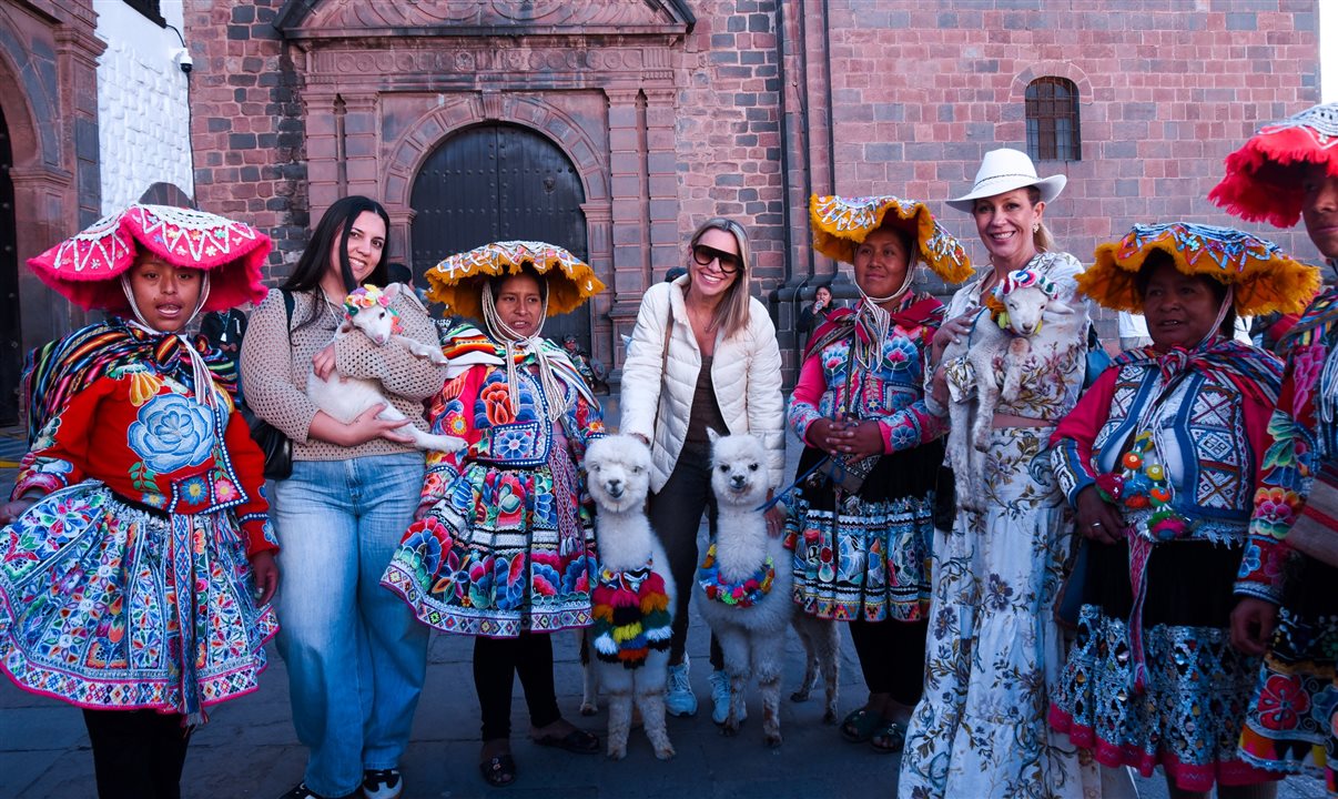 As líderes da Luxperts com lhamas e mulheres com roupas típicas peruanas no centro de cusco