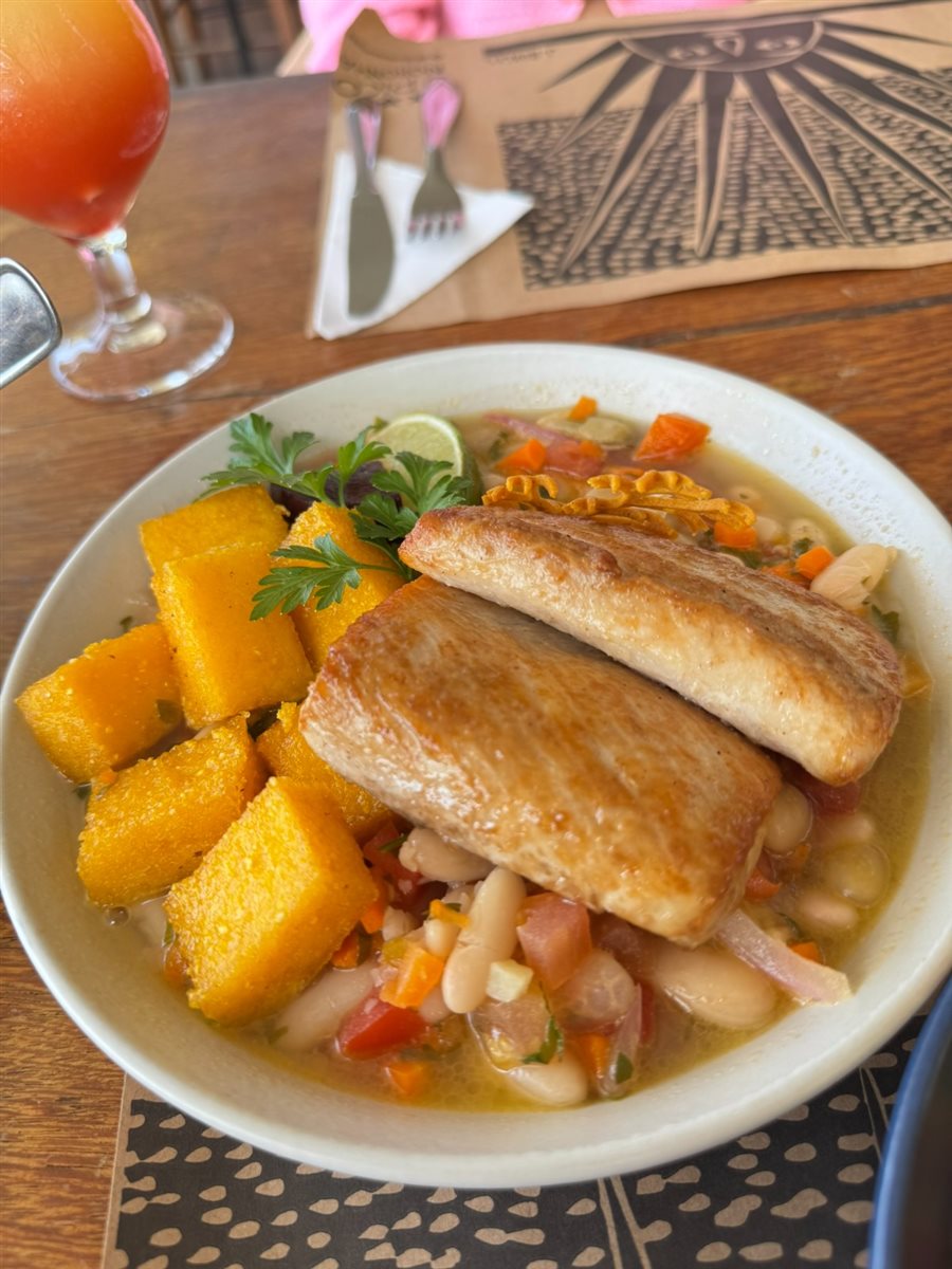 Peixe Clássico servido com feijão branco, polenta e mais especiarias mergulhados em um caldo cítrico