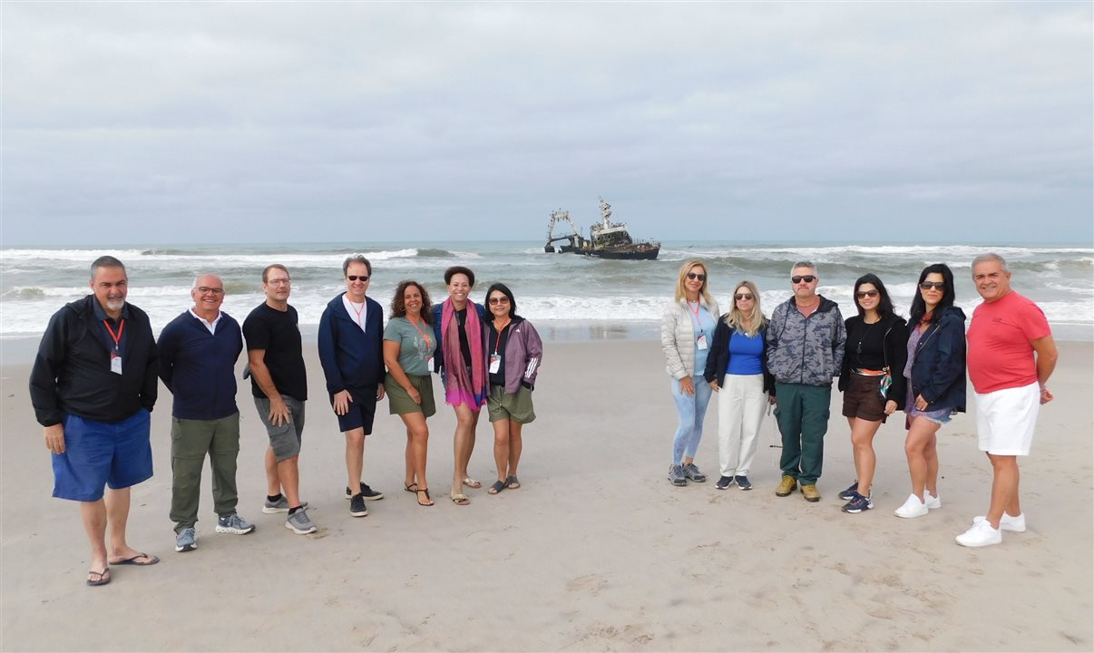 O grupo do fam da Flot posa com o navio ao fundo