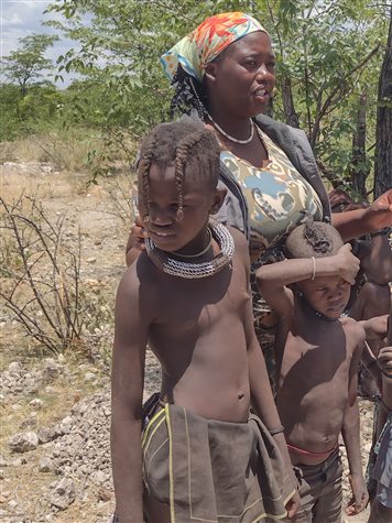 A guia Melody e duas crian&ccedil;as Himba &ndash; uma garota, &agrave; esq., e um menino &ndash; durante visita na aldeia