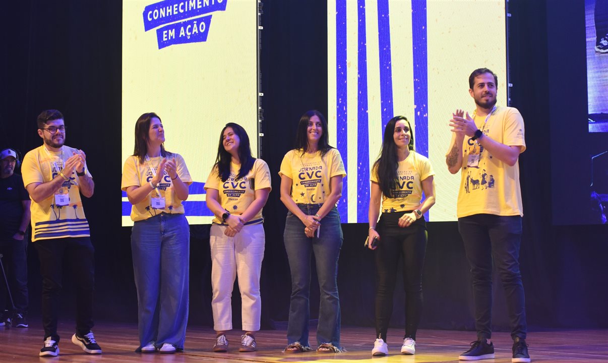 Parte do time internacional no palco: Paulo Biondo (Redes Globais e Regionais), Janaina Maria (América do Norte), Barbara Saiton (Conectividade e Brokers), Nathalia Pacheco (Produto Internacional), Vivian Amaral (Caribe) e Yago Masid (América do Sul)