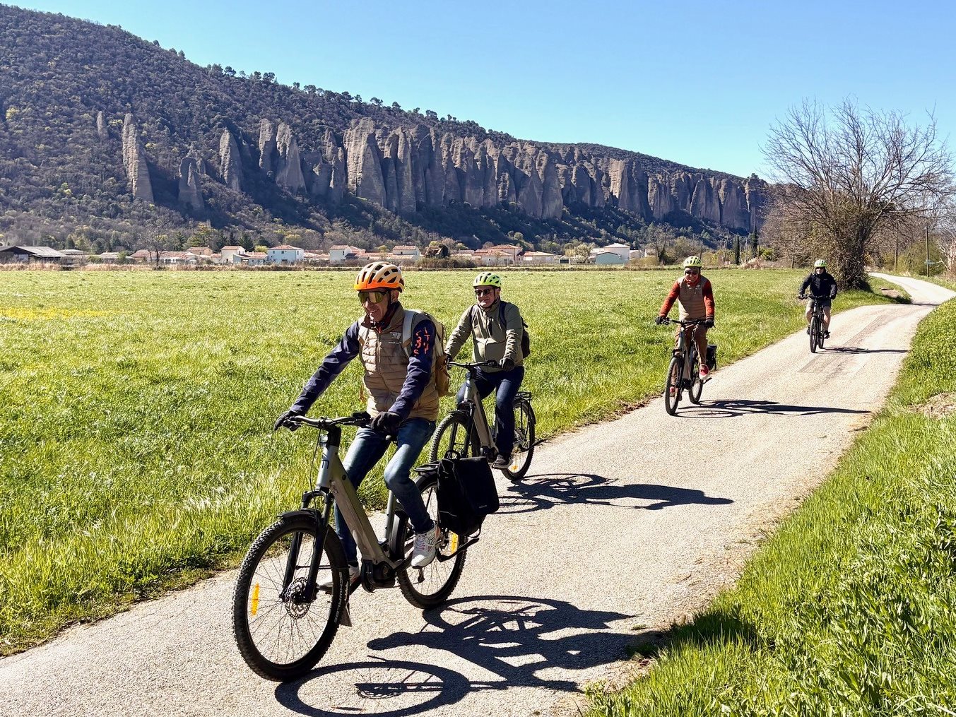 Agentes de viagens pedalam em frente à montanha rochosa Pénitents des Mées na Provence