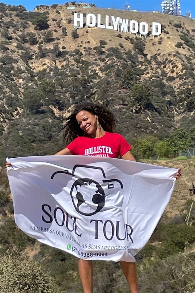 Mulher negra, viajante e empoderada: Flavia mostra a bandeira da Soul Tour em uma de suas viagens internacionais