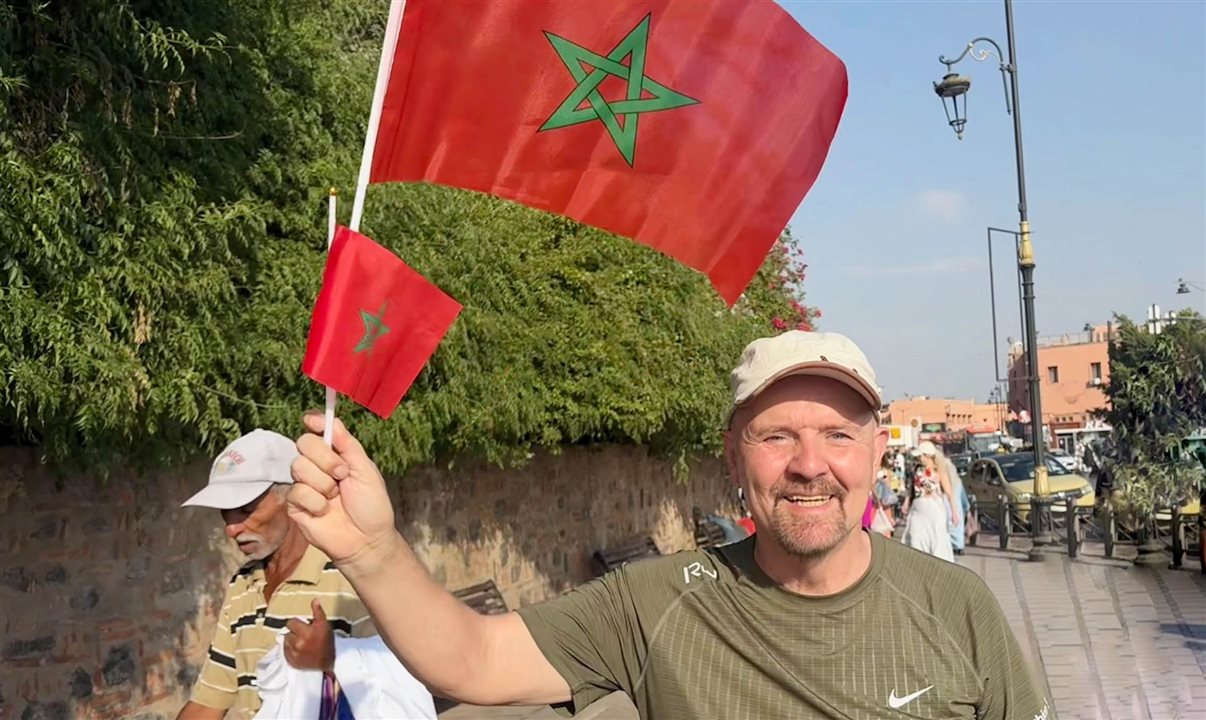 Pablo Bernhard, da TT Operadora, caminha com bandeiras do Marrocos na Praça Jemaa el Fnaa em Marrakech