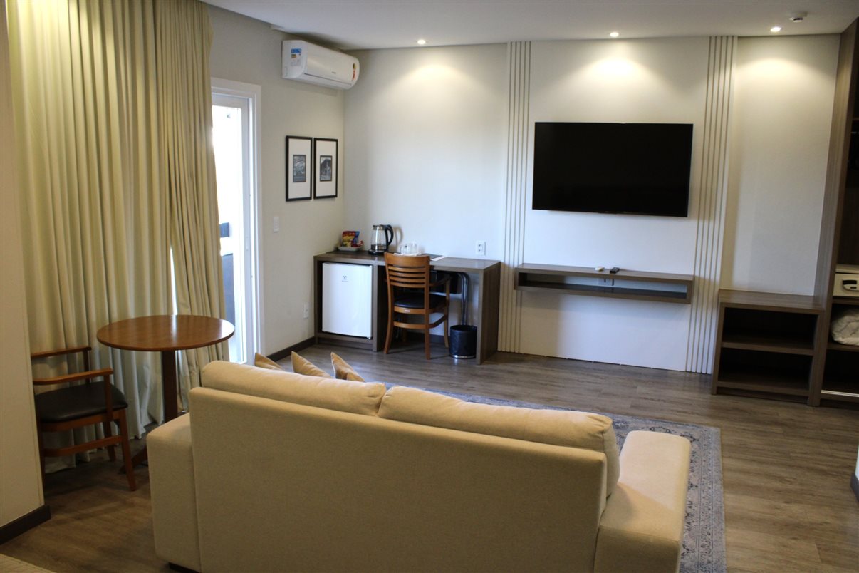 &Aacute;rea de estar com sof&aacute; e TV